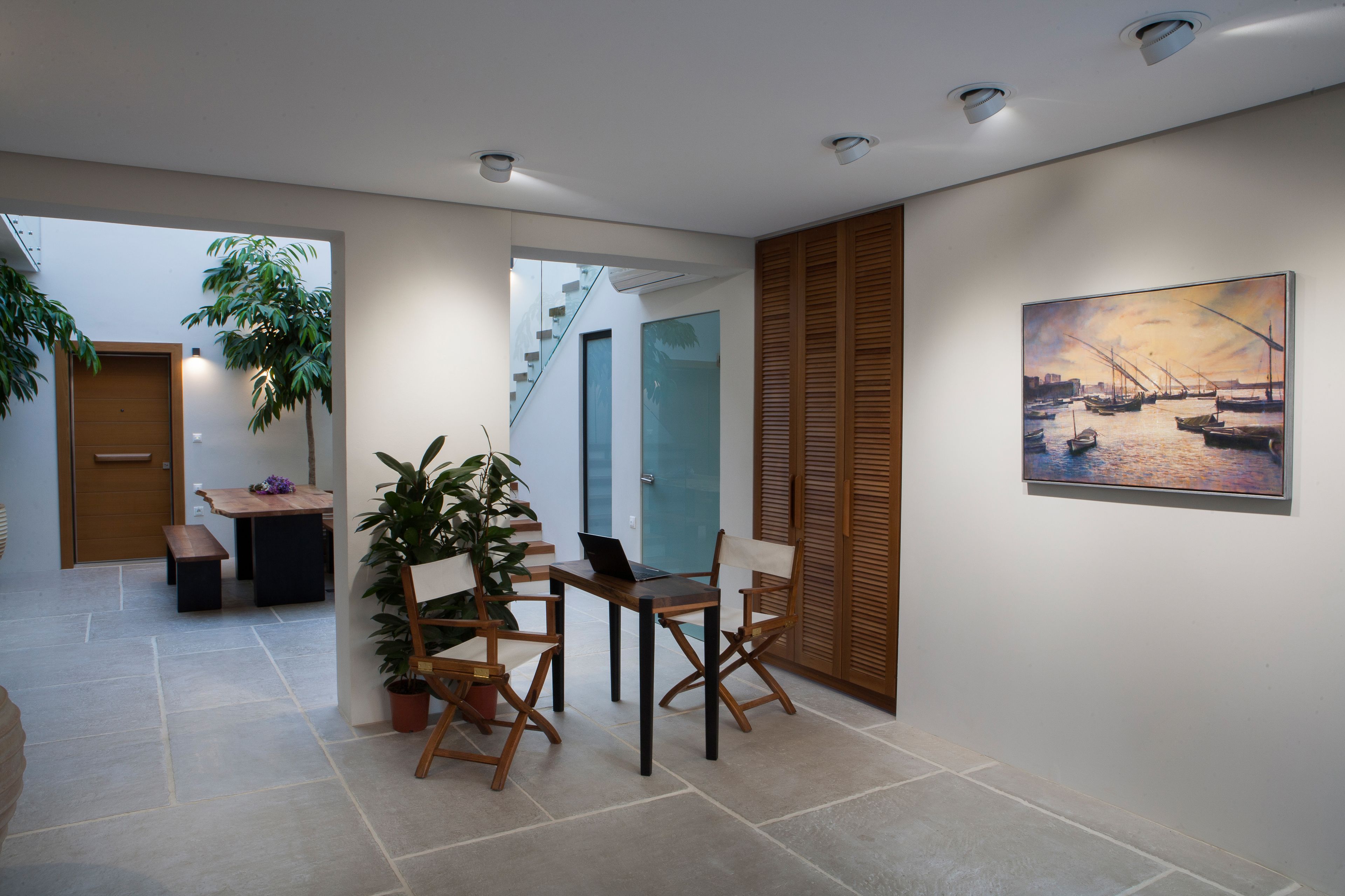 Um interior moderno com área de refeições, escada e um quadro na parede.