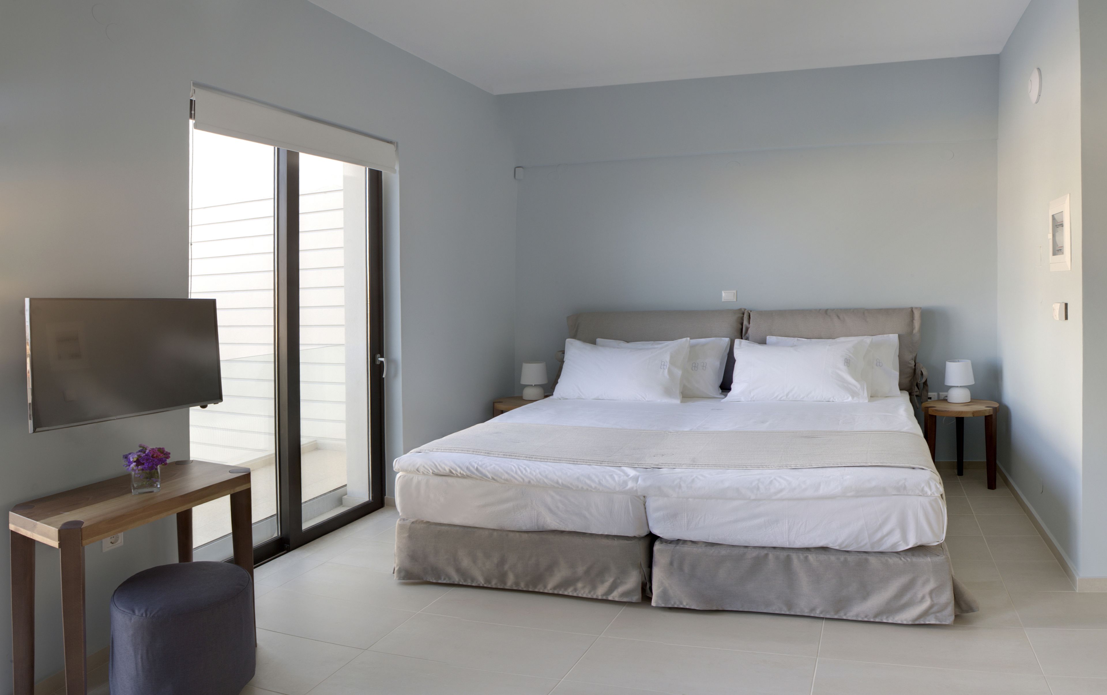A bedroom with a bed, a TV, a desk, and a chair.