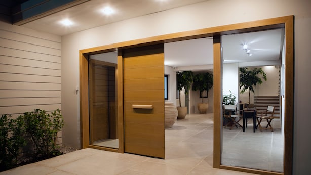 A modern interior with a sliding glass door leading to a dining area with a table and chairs. - Aethrion Homes (Chania)
