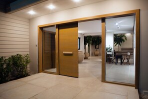 A modern interior with a sliding glass door leading to a dining area with a table and chairs. - Aethrion Homes (Chania)