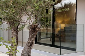 Contemporary building with a glass facade, surrounded by mature trees.