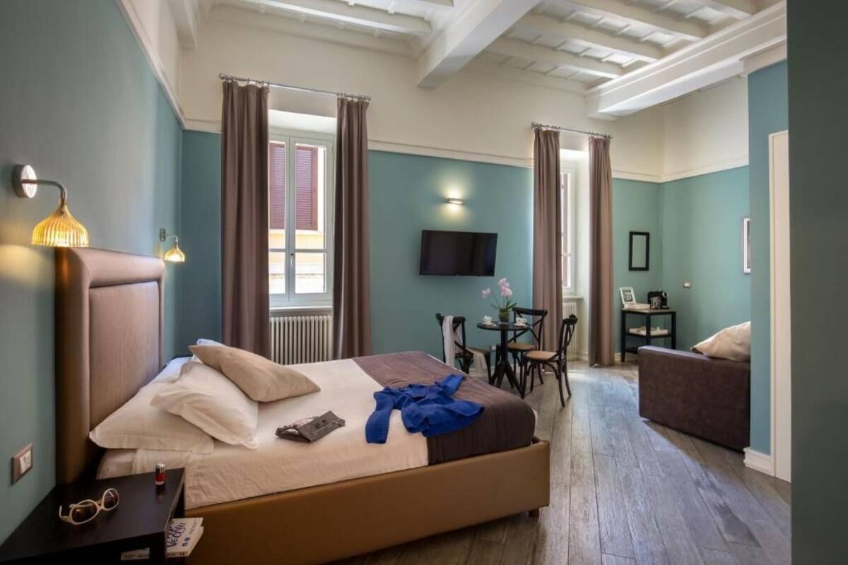 Una habitación de hotel con una cama grande, un escritorio con una silla, un televisor y un sofá.