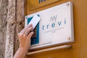 A hand placing a card into a slot on a signboard for 'trevi Charming & Luxury Rooms Rome'. - My Trevi Charming & Luxury Rooms (Rome)
