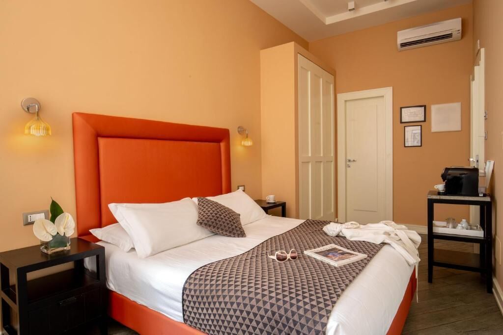 A hotel room with a large bed, a nightstand, a desk, and a door.