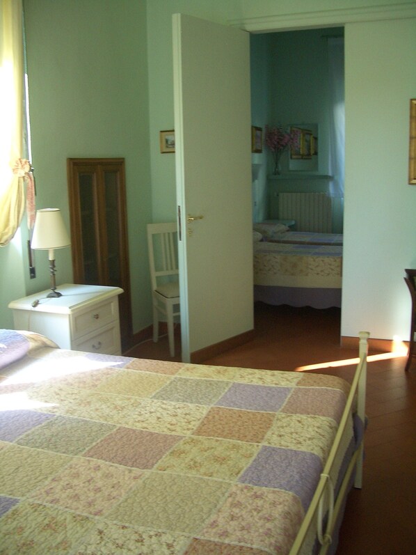 A bedroom with a bed, a nightstand, a chair, a dresser, and a door leading to another room. - B&B Lucca Porta S. Anna (Lucca)