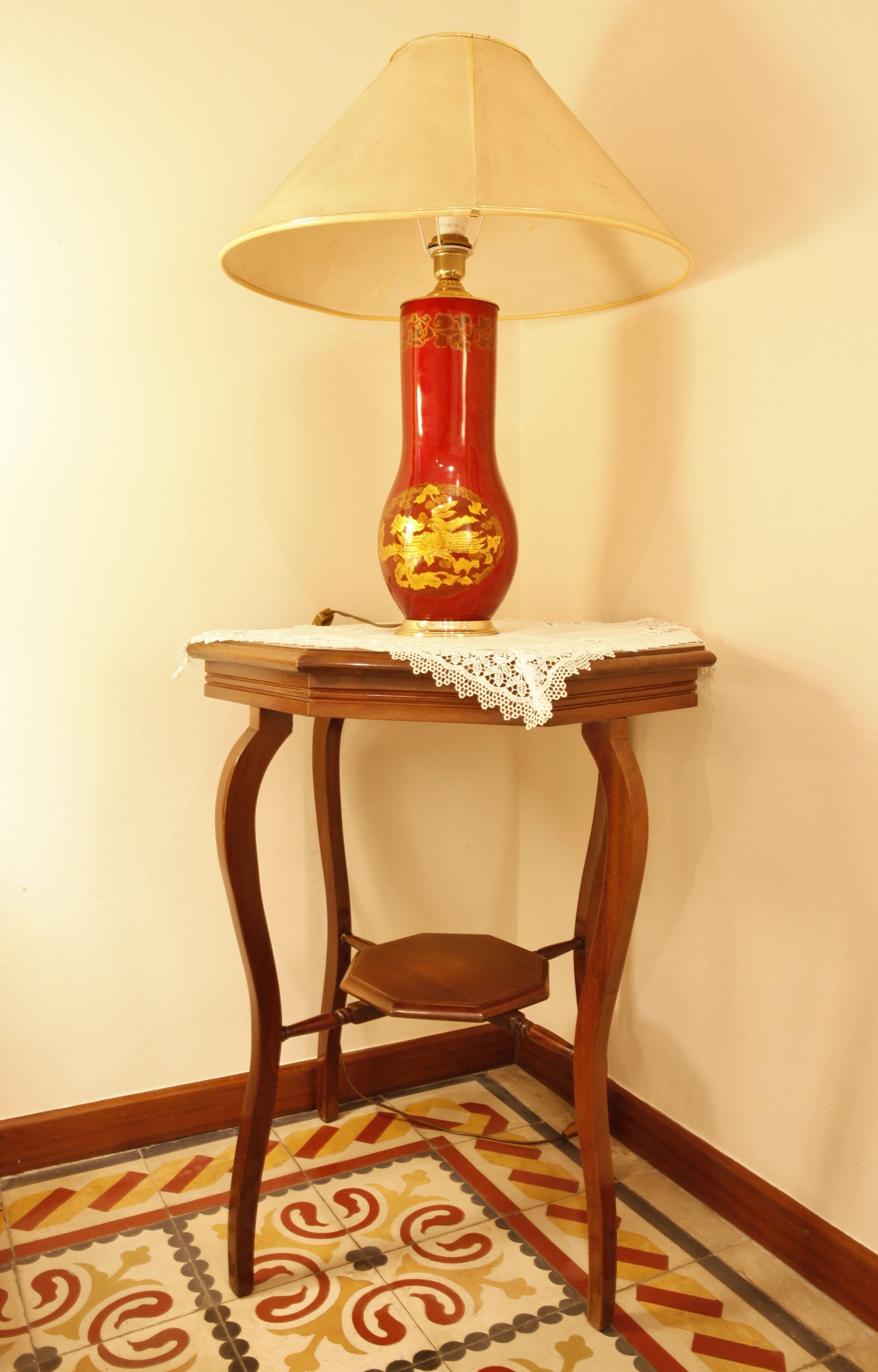 A corner table with a red vase and a lamp.