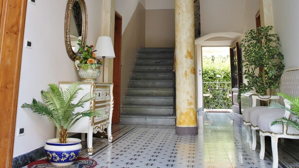A grand hallway with a tiled floor, a staircase, and a large mirror. - Lucca Relais (Lucca)