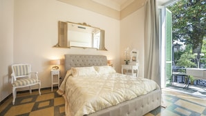 A bedroom with a large bed, a chair, a nightstand, a mirror, and a view of the outdoors. - Lucca Relais (Lucca)