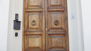 A double wooden door with a metal decorative arch above it, a small mailbox to the left, and a house number '221' on the right. - Lucca Relais (Lucca)