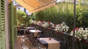 An outdoor patio with tables and chairs, surrounded by a metal fence and flowering plants. - Lucca Relais (Lucca)