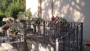 A staircase with a wrought iron railing, potted plants, and a gate. - Lucca Relais (Lucca)