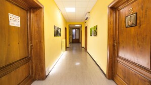 Un pasillo con puertas de madera, suelo de baldosas y un cartel con los horarios del desayuno.