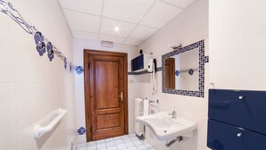 Baño con puerta de madera, lavamanos blanco y paredes de azulejos azules.