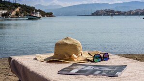 Escena de playa con un sombrero, gafas de sol y una revista sobre una toalla.