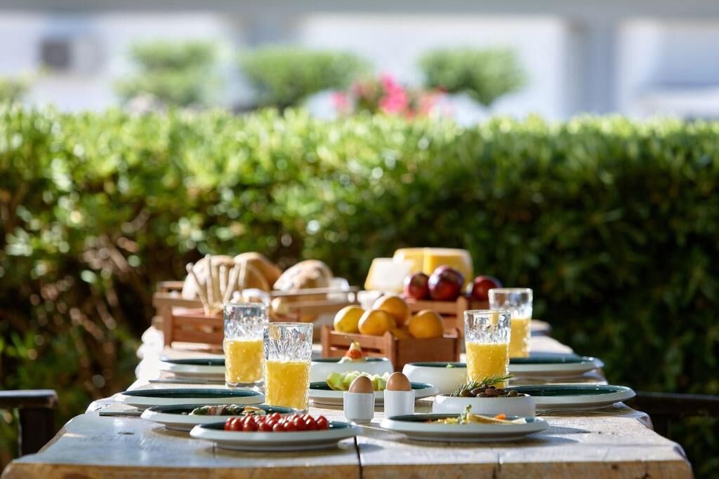 A table set outdoors with plates, glasses, and a fruit basket.