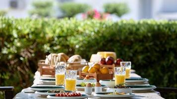 A table set outdoors with plates, glasses, and a fruit basket.