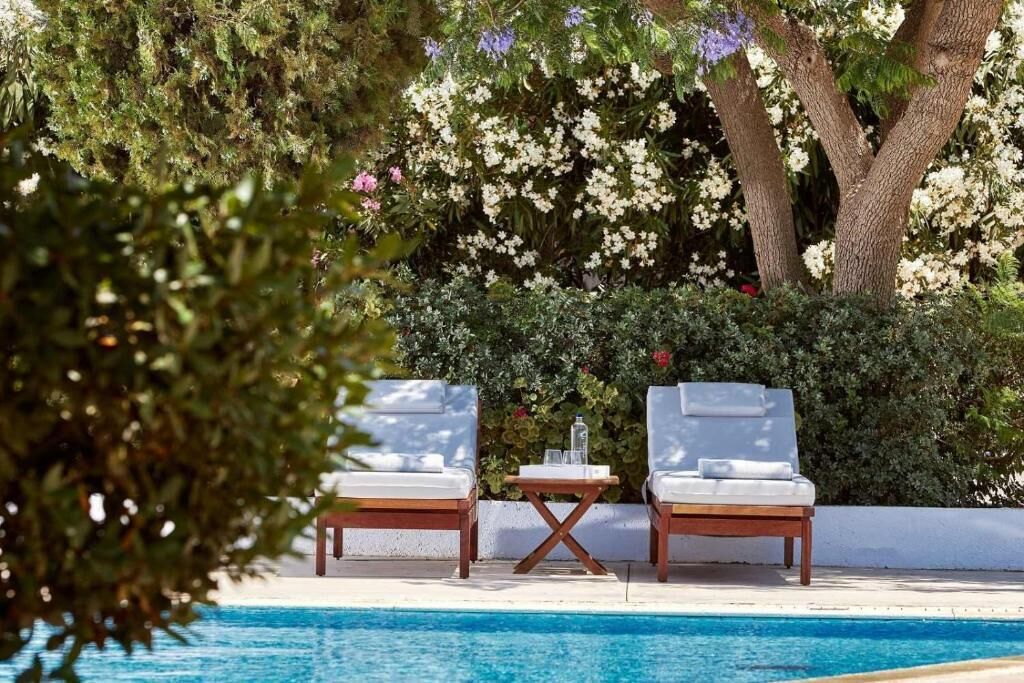 A poolside area with two lounge chairs, a small table, and a pool.