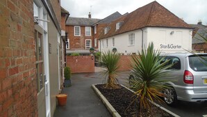 Une ruelle étroite, avec un bâtiment en briques sur la gauche et un bâtiment blanc portant une enseigne « Star & Garter » sur la droite. Deux plantes en pot sont disposées le long de la ruelle.