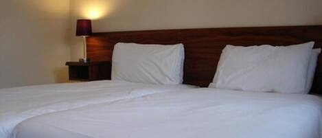 A neatly made bed with white linens in a hotel room.