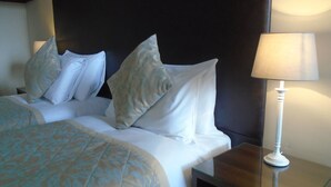 Un lit bien fait, avec une couvre-lit à motifs, une tête de lit sombre et une lampe de chevet.