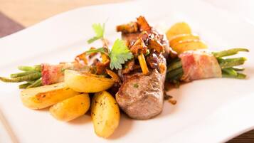 A plate of food with meat, potatoes, and herbs.