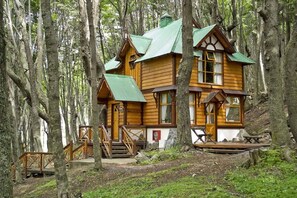 Una cabaña de madera con techo verde ubicada en un bosque.