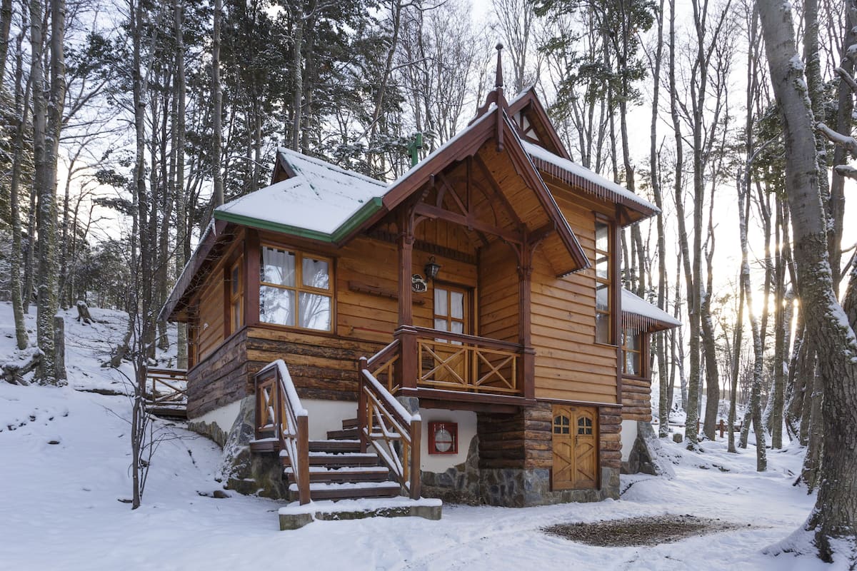 A log cabin with a wooden exterior, a porch, and a staircase leading to the entrance.