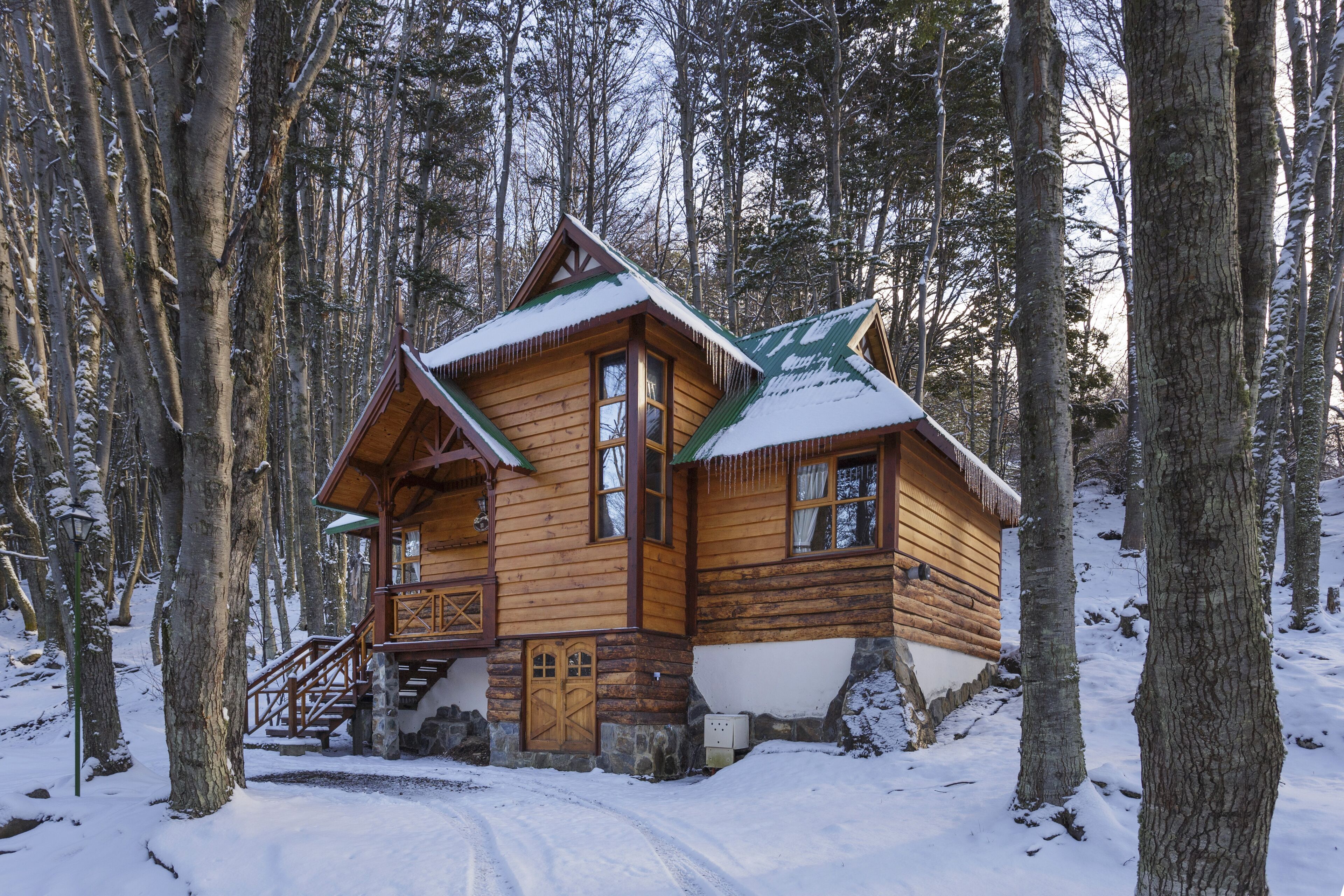 A wooden cabin with a steep roof, surrounded by snow-covered trees.