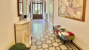 A hallway with a checkered floor, a white bench, and a large framed painting on the wall.
