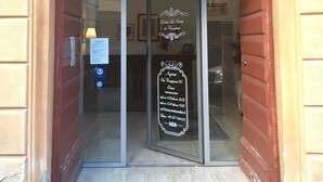 A hotel entrance with a sign indicating 'Relais La Corte dei Cavalieri' and reception hours.