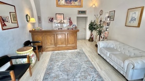 A living room with a white sofa, a wooden cabinet, a patterned rug, and various framed pictures on the walls.