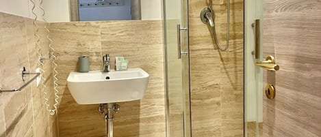 Un baño moderno con ducha envuelta en vidrio, lavamanos con espejo y un inodoro.