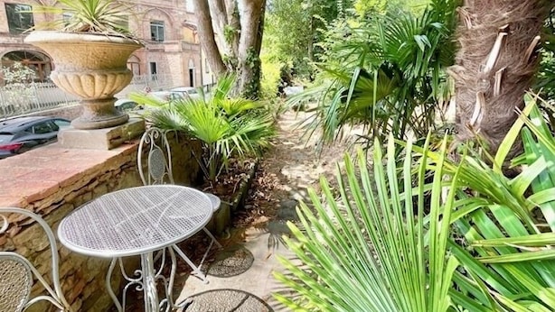A courtyard with outdoor seating, a large planter, and a building in the background.