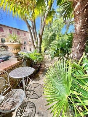 A courtyard with outdoor seating, a large planter, and a building in the background. - Relais La Corte Dei Cavalieri (Siena)