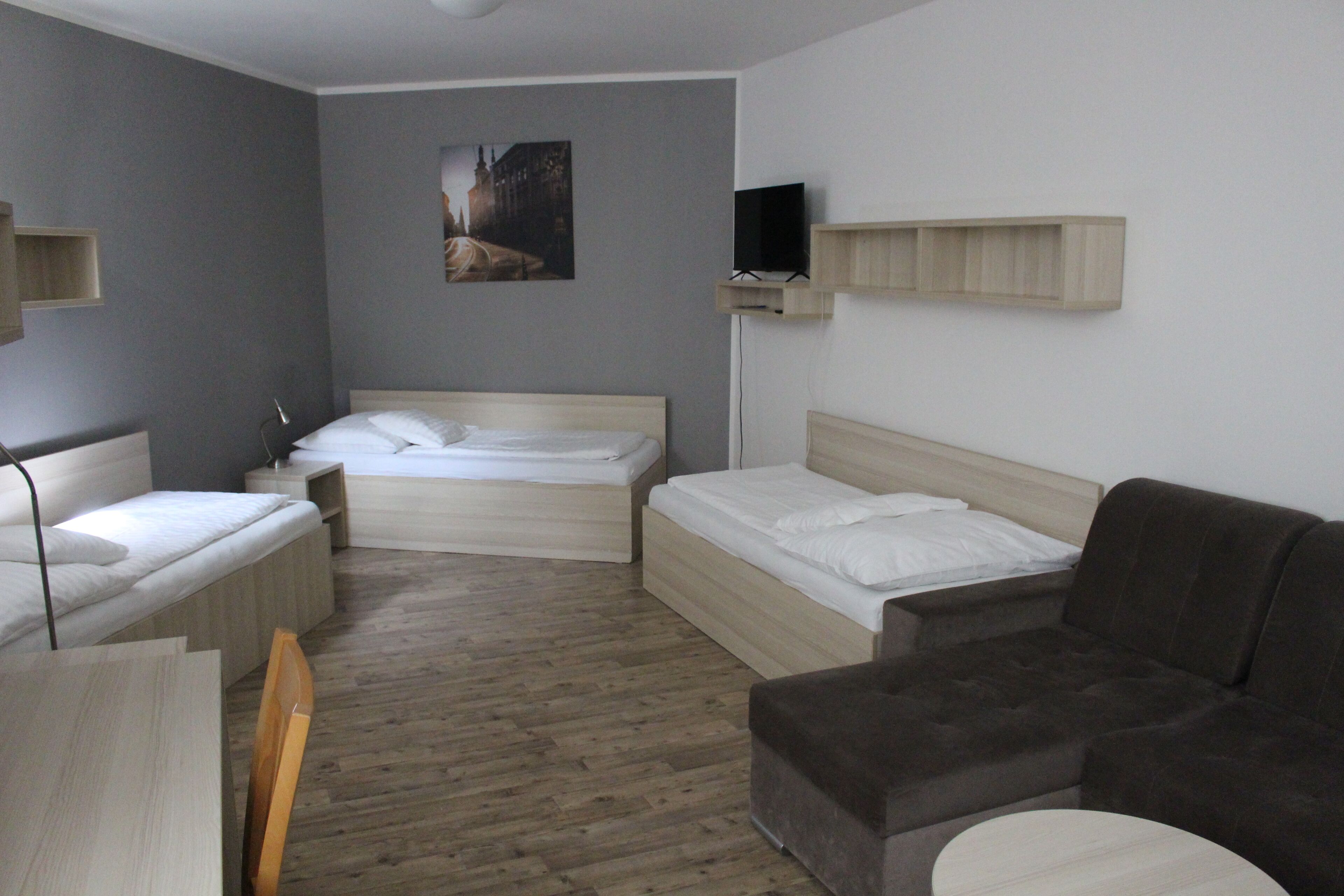 A hotel room with two beds, a sofa, a TV, and a painting on the wall.