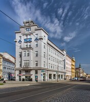 A multi-story hotel with a prominent 'HOTEL PALAC' sign, featuring a classic architectural style with a flat roof and symmetrical windows.