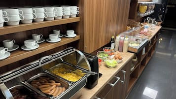 A buffet area with various food options, including meats, eggs, and salads.