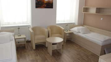 A room with a bed, two armchairs, a small table, and a painting on the wall.