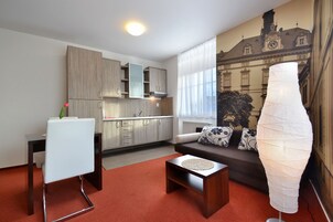 A modern living room with a sofa, a dining table, and a kitchen area.