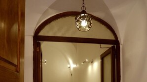 A hallway with a wooden door, a staircase, and a hanging light fixture. - Vicolo del lupo Guesthouse (Rome)