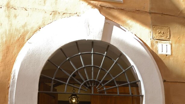 An arched doorway with a metal grille, wooden doors, and a small step leading into a building. - Vicolo del lupo Guesthouse (Rome)