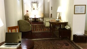 A traditional room with a wooden ceiling, a dining table with chairs, a sofa, and a patterned rug. - Vicolo del lupo Guesthouse (Rome)