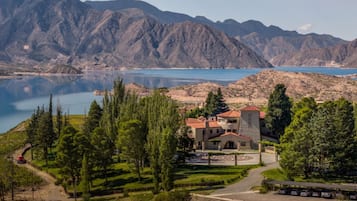 Un edificio con tejado rojo, rodeado de árboles y montañas al fondo.