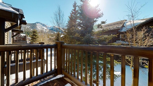 A wooden deck with a view of a snow-covered landscape and mountains.