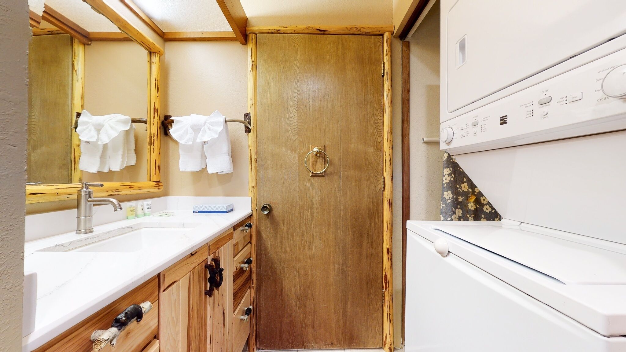 Une petite salle de bain avec une porte en bois, un lavabo avec un miroir et un lave-linge blanc.