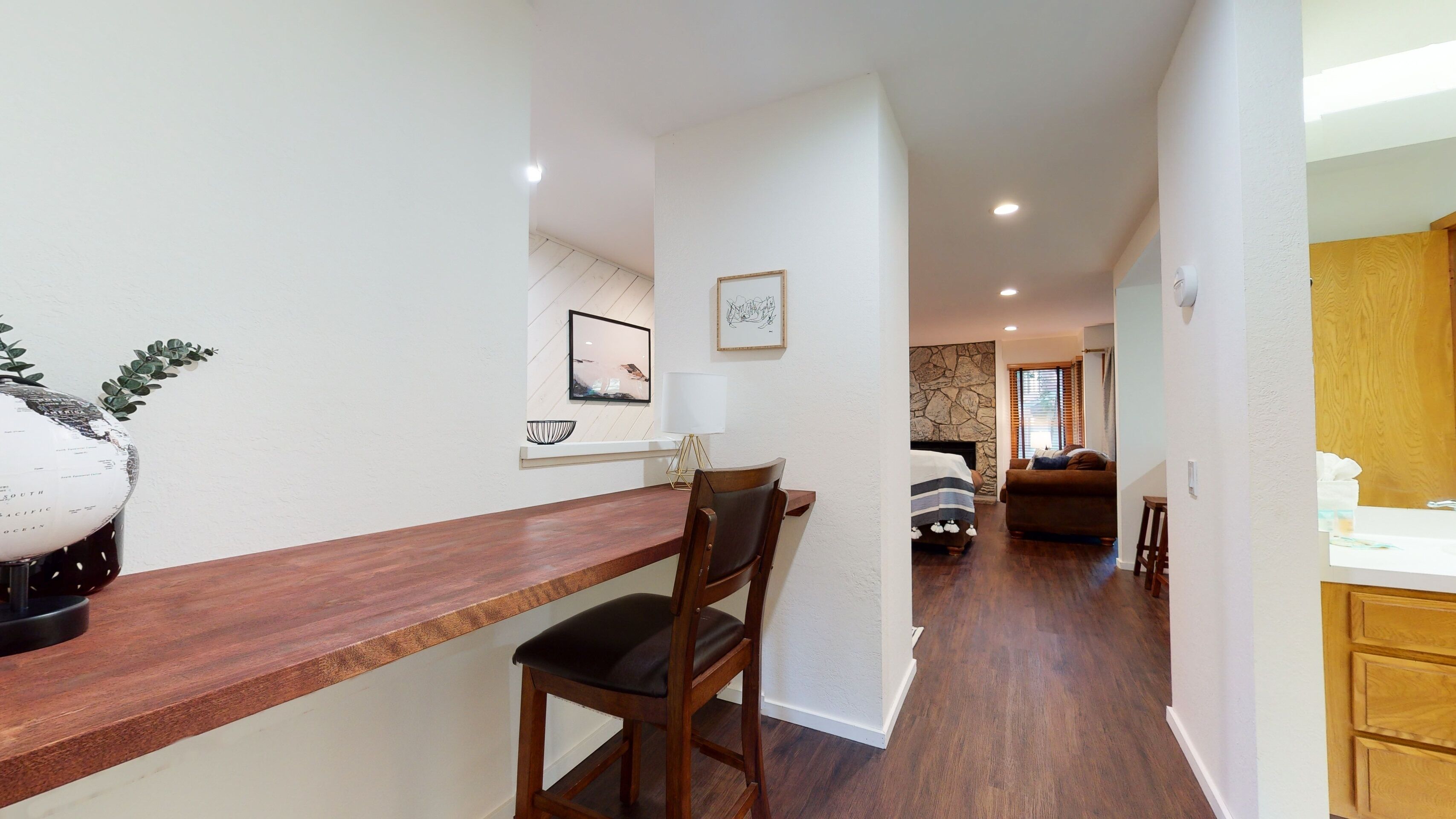Une cuisine moderne avec des plans de travail en bois, un coin repas avec une chaise en bois, et un salon avec un canapé et une cheminée.