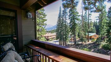 A wooden deck with a view of a forest and mountains.