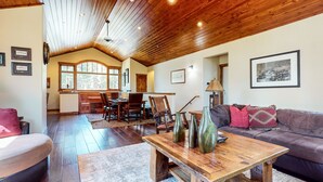 A spacious living room with a wooden ceiling, a dining area with a large window, and a cozy seating area with a couch and a coffee table. - Graystone 2088 4 Bedroom Home by RedAwning (Mammoth Lakes)