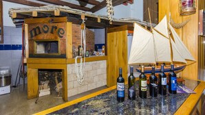 A rustic bar area with wooden beams, a wooden counter, and a sailboat model. There are bottles of wine on the counter. - Palma Rooms B&B (Split)