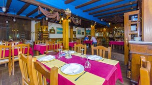 A restaurant with wooden beams, tables set with white plates and pink tablecloths, and a bar area in the background. - Palma Rooms B&B (Split)